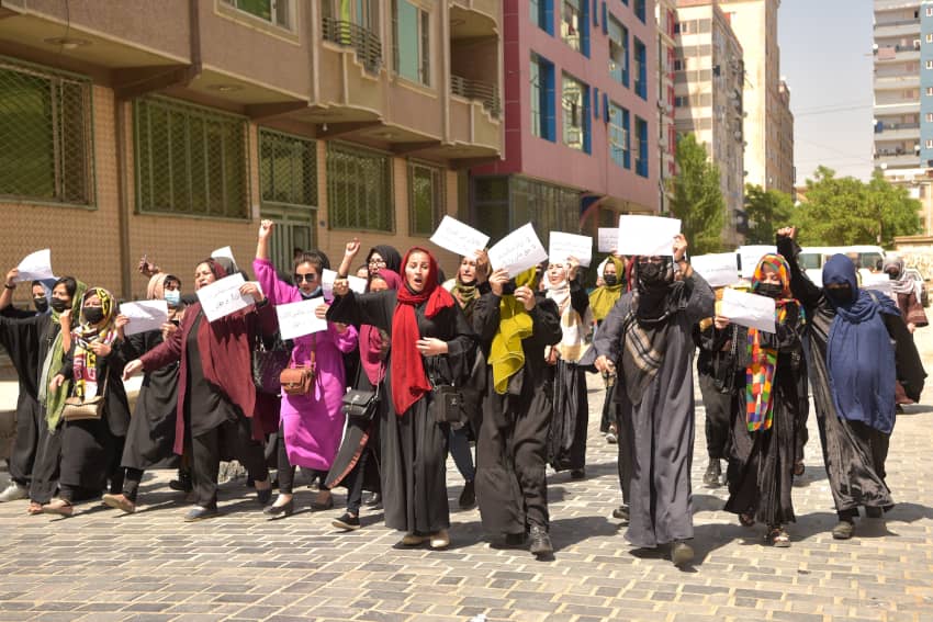 Un grupo de mujeres afganas protestan por sus derechos con pancartas y los brazos en alto